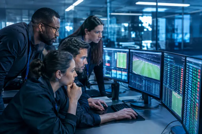 Operations staff monitor trading alerts and account checks on multiple screens